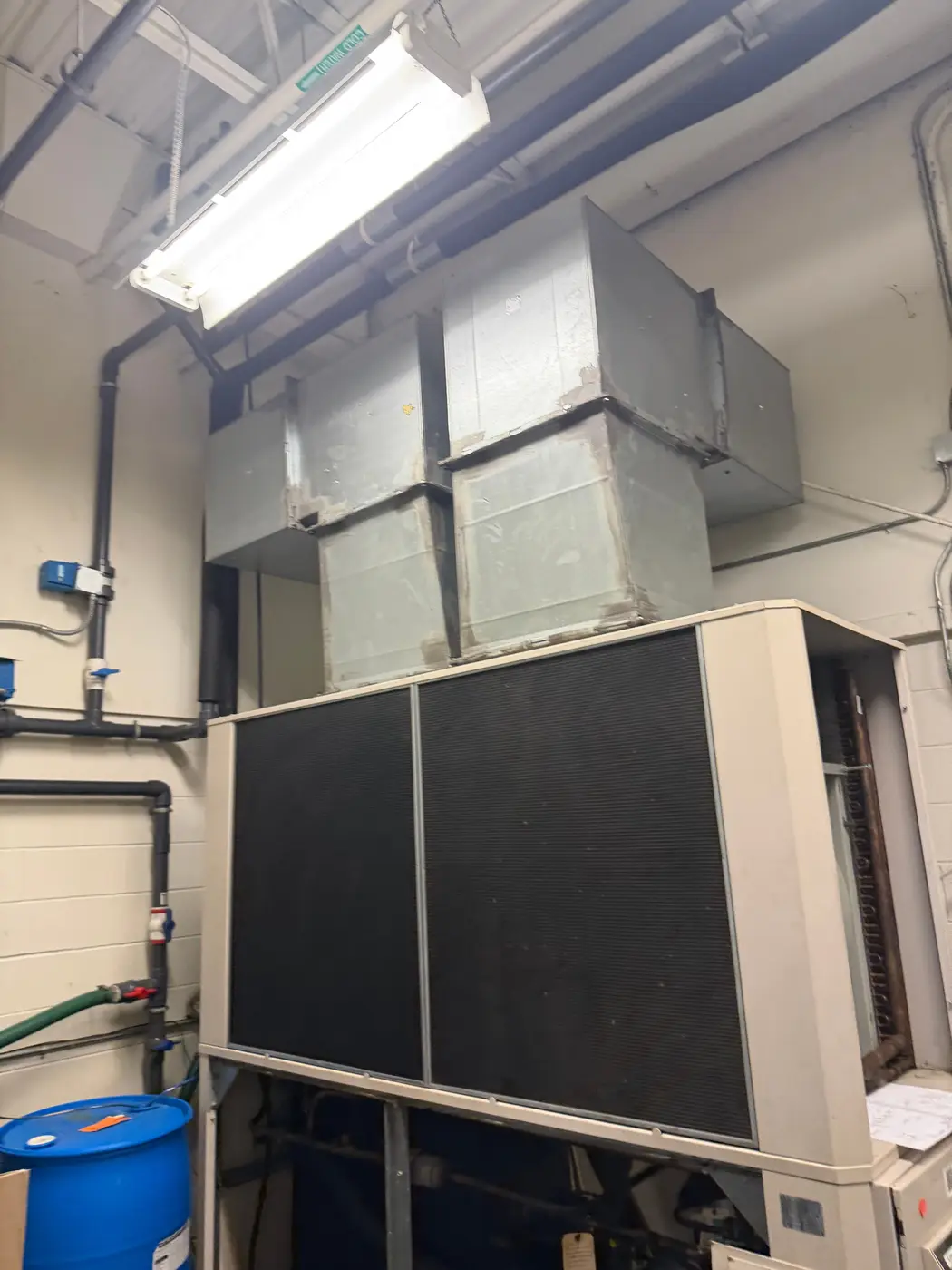 Large indoor HVAC unit with sheet-metal ductwork in a commercial mechanical room