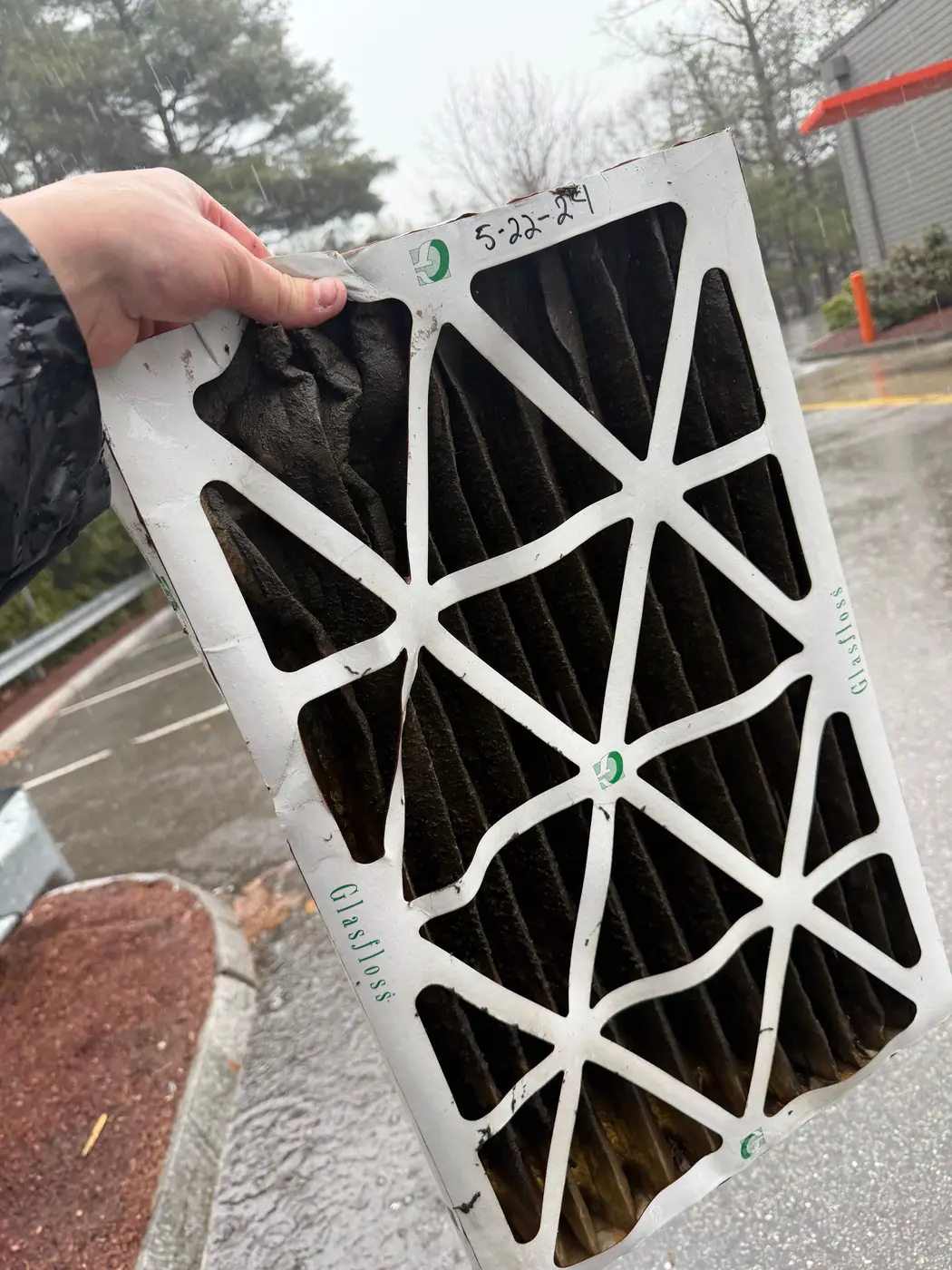 Clogged pleated air filter held up after being pulled from a unit