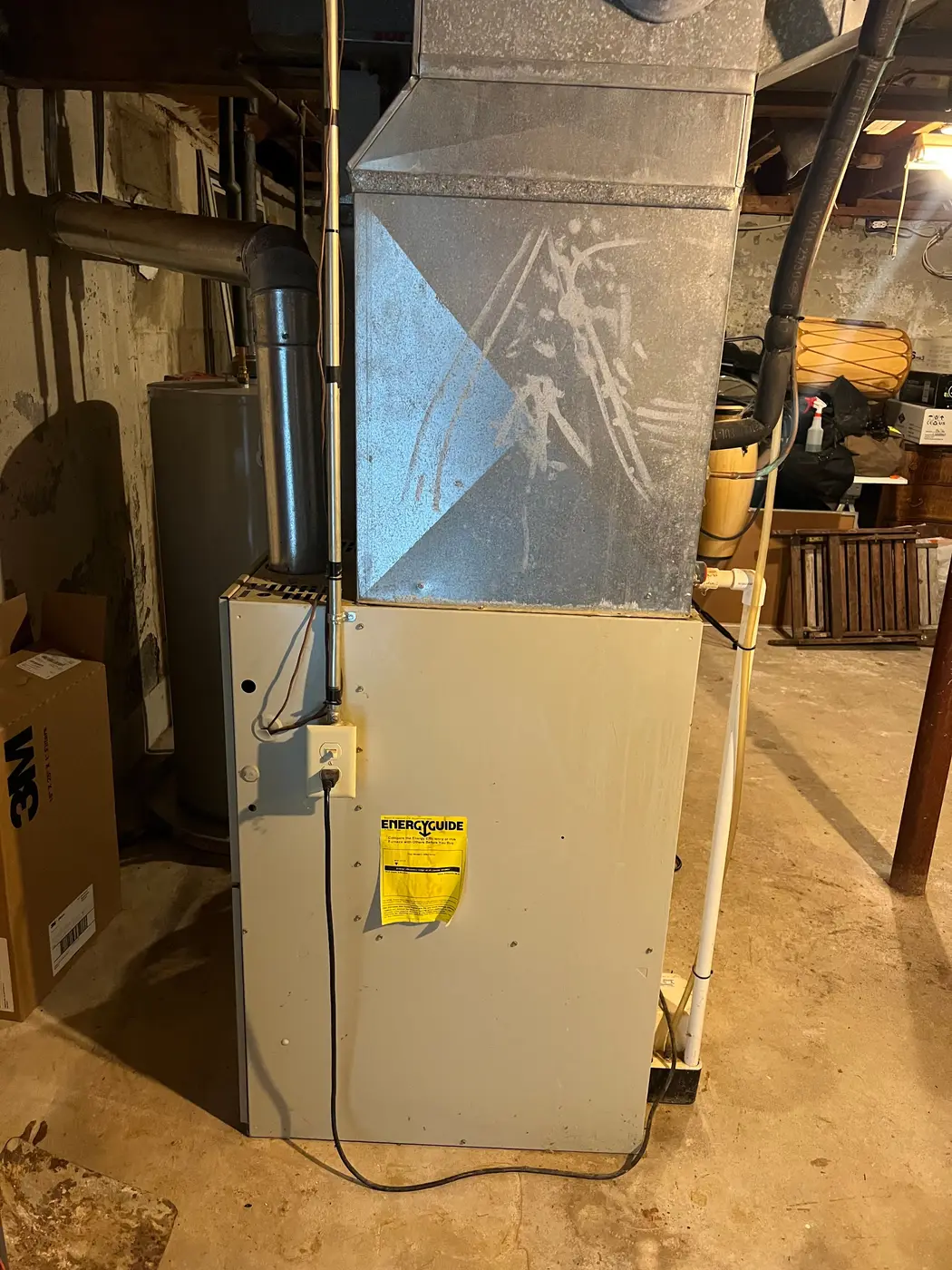 Furnace in an unfinished basement with a sheet-metal supply plenum above it