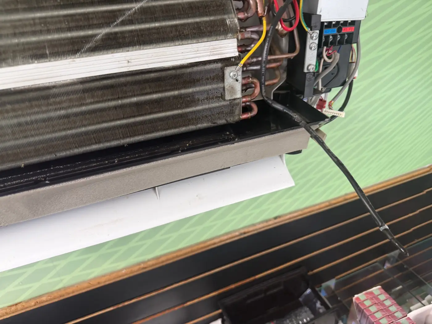 Mini-split head with the front cover off, showing the indoor coil and wiring