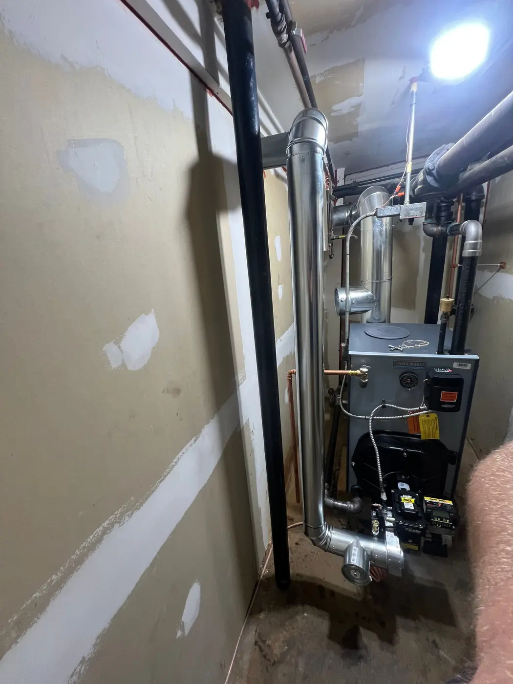 Boiler with an oil burner and a stainless flue pipe in a small utility room